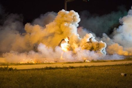 © Reuters. Manifestante joga de volta uma bomba de fumaça em confronto com a polícia em Ferguson, Missouri, nos EUA