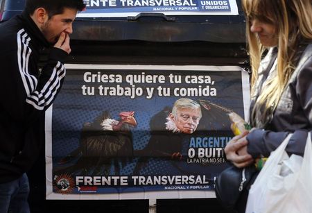 © Reuters. People walk past a poster depicting U.S. Judge Griesa as a vulture in Buenos Aires