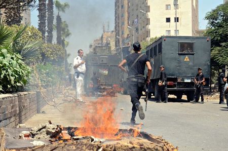 © Reuters. Police take positions after a protest was dispersed quickly, leaving fire burning in a main street in Giza, south of Cairo