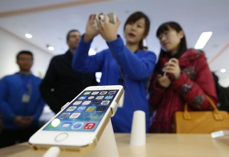 © Reuters. Funcionária explica o funcionamento de um iPhone 5, em Pequim