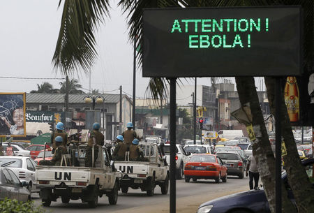 © Reuters. A U.N. convoy of soldiers passes a screen displaying a message on Ebola on a street in Abidjan