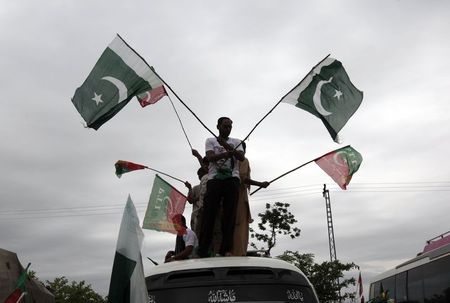 © Reuters. Supporters of Pakistan Tehreek-e-Insaf, a political party led by cricketer-turned-opposition politician Imran Khan, wave flags from the roof of a van as they arrive with the Freedom March in Islamabad