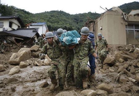 © Reuters. JSDF soldiers and police officers carry the body of a victim in a plastic bag at a site where a landslide swept through a residential area at Asaminami ward in Hiroshima