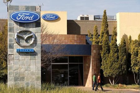 © Reuters. Workers walk near the logos of Ford and Mazda Motor Co at the company's assembly plant in Pretoria