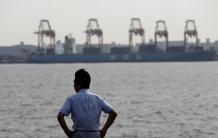 © Reuters. A businessman stands near a cargo area at a port in Tokyo