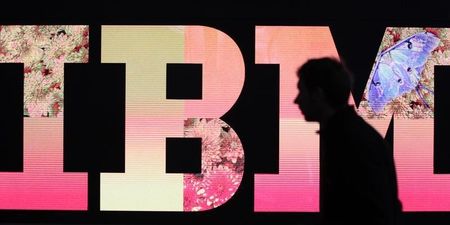 © Reuters. A man passes by an illuminated IBM logo at the CeBIT computer fair in Hanover