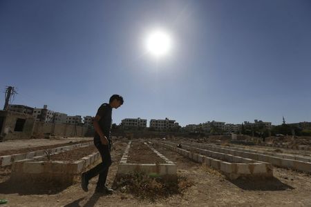 © Reuters. Homem passa por covas coletivas de mortos durante ataque químico em Zamalka, nos arredores de Damasco