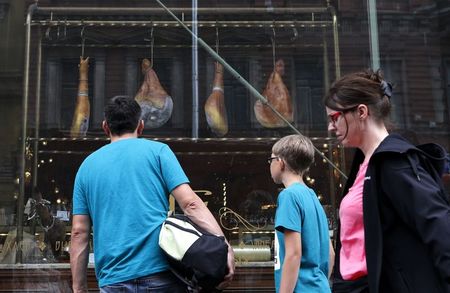 © Reuters. People pass by a shop window displaying Spanish ham for sale at a grocery store in St. Petersburg