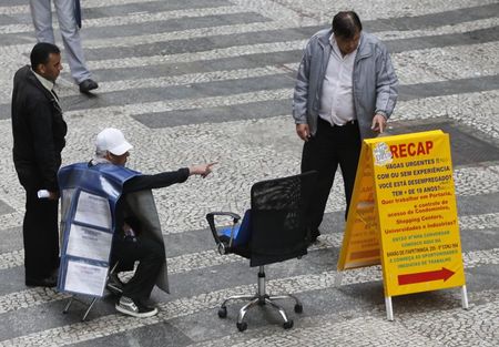 © Reuters. A job promoter points to a list of job offers posted in a main street in downtown Sao Paulo