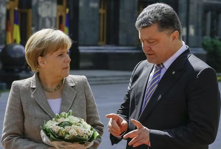 © Reuters. Merkel looks on as Poroshenko gestures in Kiev