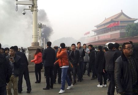 © Reuters. File photo of people walking along the sidewalk of Chang'an Avenue as smoke rises in front of the main entrance of the Forbidden City at Tiananmen Square in Beijing