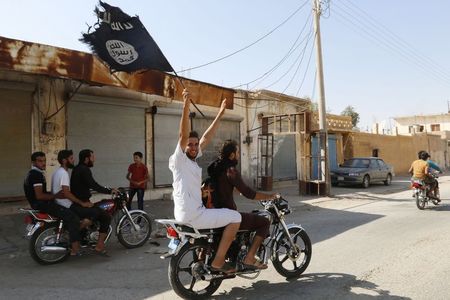 © Reuters. Resident of Tabqa city touring the streets on a motorcycle waves Islamist flag in celebration after Islamic State militants took over Tabqa air base, in nearby Raqqa city