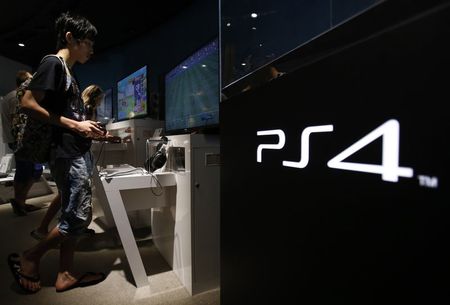 © Reuters. Люди играют в приставки PlayStation 4 в шоу-руме Sony Corp в Токио