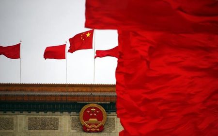 © Reuters. Red flags flutter next to a national emblem and a national flag of China on top of the Great Hall of the People, which is the venue of the closing ceremony of the CPPCC, in Beijing