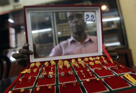 © Reuters. Продавец ювелирного магазина в Коломбо демонстрирует золотые сережки