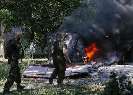 © Reuters. Separatistas pró-Rússia passam por local em chamas que, segundo testemunhas, foi atacado por bombardeio da Ucrânia