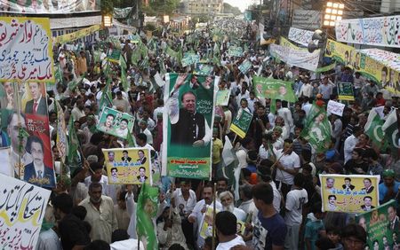 © Reuters. Supporters of Pakistan Muslim League-Nawaz (PML-N) party, carry posters and national flags as they participate in pro-government rally in support of Prime Minister Nawaz Sharif, in Lahore