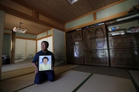 © Reuters. Watanabe holds a portrait of his late wife Hamako at his home at Yamakiya district in Kawamata town, Fukushima prefecture