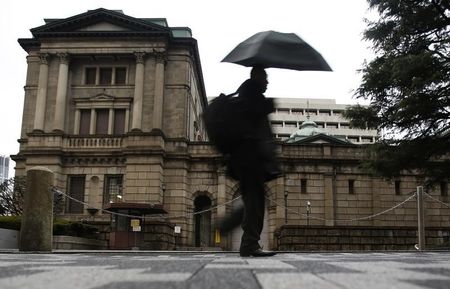© Reuters. A pedestrian holding an umbrella to take shelter from rain and hail walks past the Bank of Japan headquarters building in Tokyo