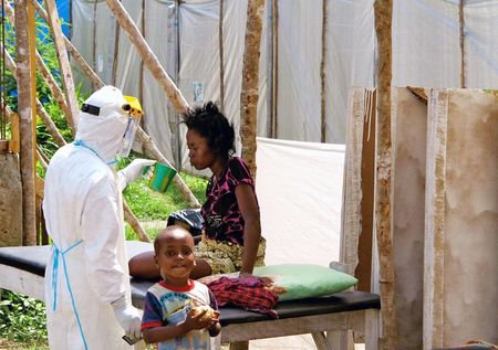 © Reuters. Trabalhador totalmente protegido oferece água a mulher com Ebola em centro de tratamento de Kenema