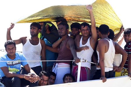 © Reuters. Migrants take shelter from the sun before disembarking a coast guard ship at the Sicilian harbour of Augusta