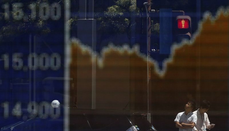 &copy; Reuters Man looks up as he is reflected on an electronic board displaying Japan's Nikkei average outside a brokerage in Tokyo