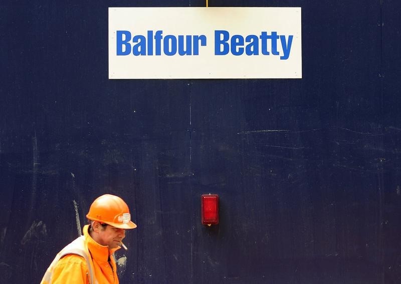 &copy; Reuters A worker strolls past a Balfour Beatty sign at a construction site in central London
