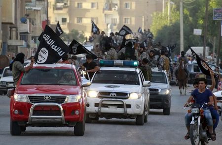 © Reuters. Militant Islamist fighters waving flags, travel in vehicles as they take part in a military parade along streets of Syria's northern Raqqa province