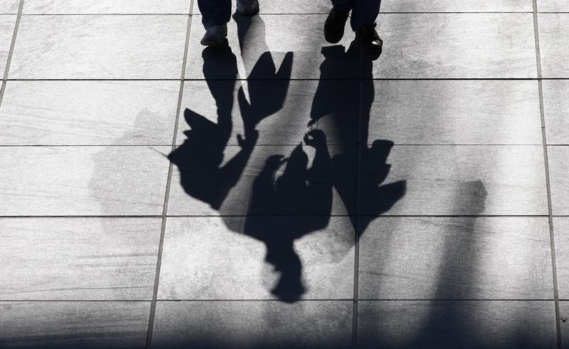 &copy; Reuters Two men cast their shadows on the street as they carry a shopping bag,  in Berlin