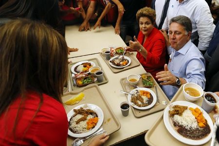 © Reuters. Presidential candidate and Brazilian President Rousseff gestures next to Governor candidate of Rio de janeiro Garotinho as they visit a popular restaurant during a re-election campaign rally in Rio de Janeiro