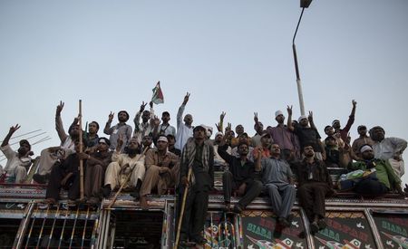 © Reuters. Supporters of Tahir ul-Qadri, Sufi cleric and leader of political party Pakistan Awami Tehreek (PAT), listen to their party leaders in front of the Parliament house building during the "Revolution March" in Islamabad