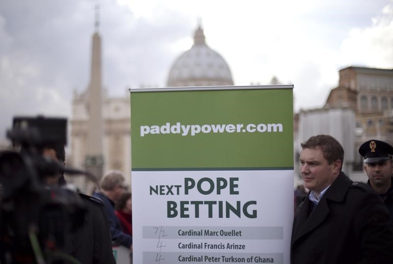&copy; Reuters A man holds an advertisement for Paddy Power, an Irish bookmaker, in front of St Peter's square, outside the Vatican