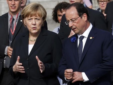 © Reuters. Germany's Chancellor Merkel talks to France's President Hollande as they arrive for a family photo after a ceremony to commemorate the centenary of the start of World War I, in Ypres