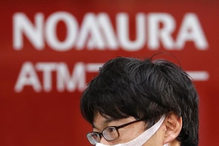 © Reuters. A man walks past a signboard of Nomura Securities outside its branch in Tokyo