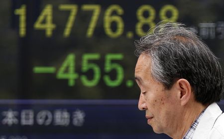 © Reuters. A pedestrian walks past an electronic board showing Japan's Nikkei average outside a brokerage in Tokyo
