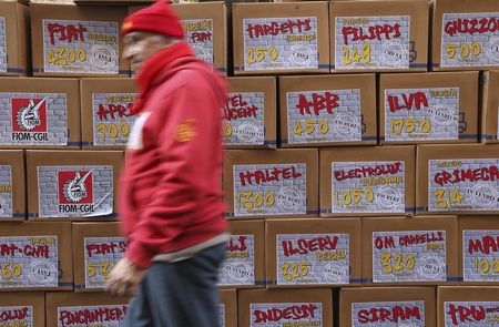 © Reuters. A worker walks past a wall of boxes, each marked with the name of a factory,  in front of the Ministry of Labour in Rome December 11, 2013