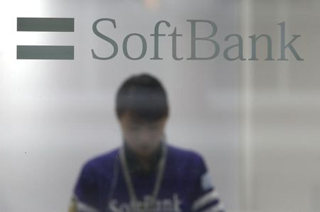 © Reuters. A shop clerk is seen through a window displaying a logo of SoftBank Corp at its branch in Tokyo