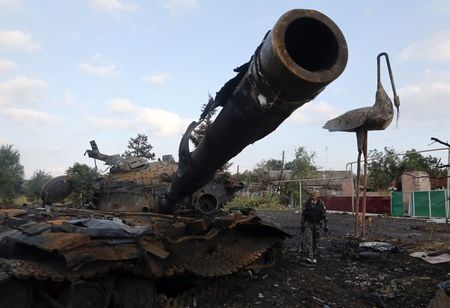 © Reuters. Pro-Russian separatist walks past a destroyed tank at Savur-Mohyla, a hill east of the city of Donetsk