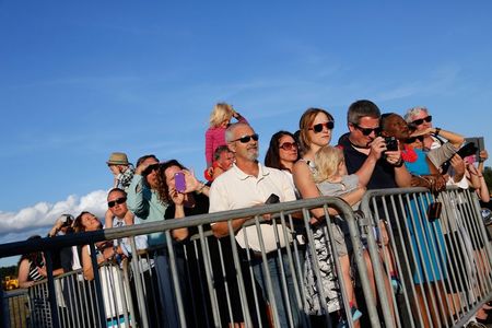 © Reuters. People wait to greet U.S. President Obama in a viewing area as he arrives via Air Force One at T.F. Green Airport in Warwick, Rhode Island