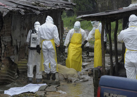 © Reuters. Health workers wearing protective clothing prepare to carry an abandoned dead body presenting with Ebola symptoms at Duwala market in Monrovia