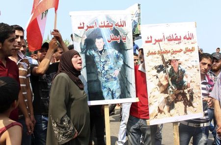 © Reuters. Relatives of captured Lebanese soldiers carry pictures of two of them during a protest demanding their release in al-Mhmara