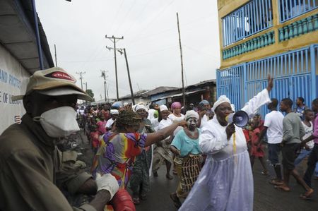 © Reuters. احتفالات في أحد أحياء ليبيريا بعد رفع الحجر الصحي عنه