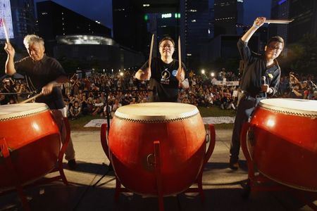 © Reuters. Founders of the Occupy Central civil disobedience movement Chu, Tai and Chan hit drums during a campaign to kick off the movement in front of the financial Central district in Hong Kong