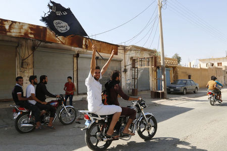 © Reuters. Moradores de Tabqa erguem bandeira do Estado Islâmico perto de Raqqa