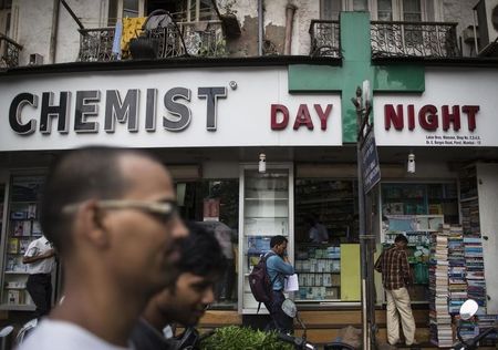 © Reuters. People walk past a chemist shop at a market in Mumbai