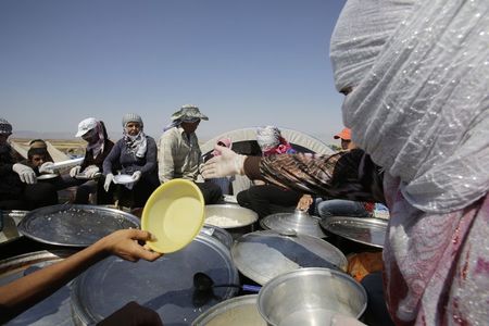 © Reuters. Moradores de Qamishli distribui comida a desabrigados da minority yazidi, no nordeste da Síria