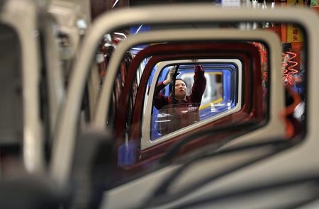 © Reuters. A worker installs rubber onto the windows of the doors along a production line at a truck factory of Anhui Jianghuai Automobile Co. Ltd in Hefei