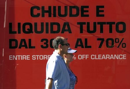 © Reuters. People walk past a retail store that is having a sale in Rome