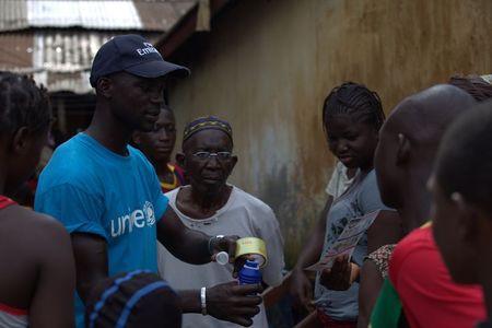 © Reuters. A UNICEF worker shares information on Ebola and best practices to help prevent its spread with residents of the Matam neighborhood of Conakry