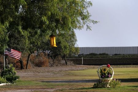 © Reuters. A U.S. flag blows in the wind in the backyard of a home facing the border fence at the United States-Mexico border outside of Brownsville